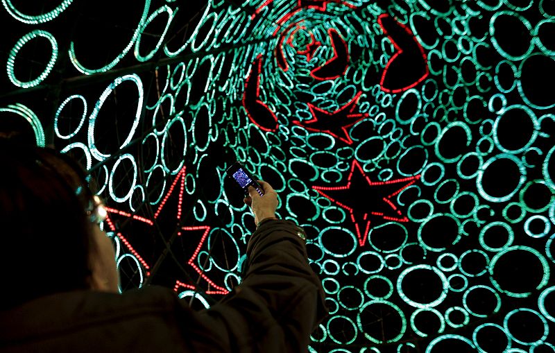 Una mujer fotografía la iluminación navideña de la Puerta del Sol de Madrid.