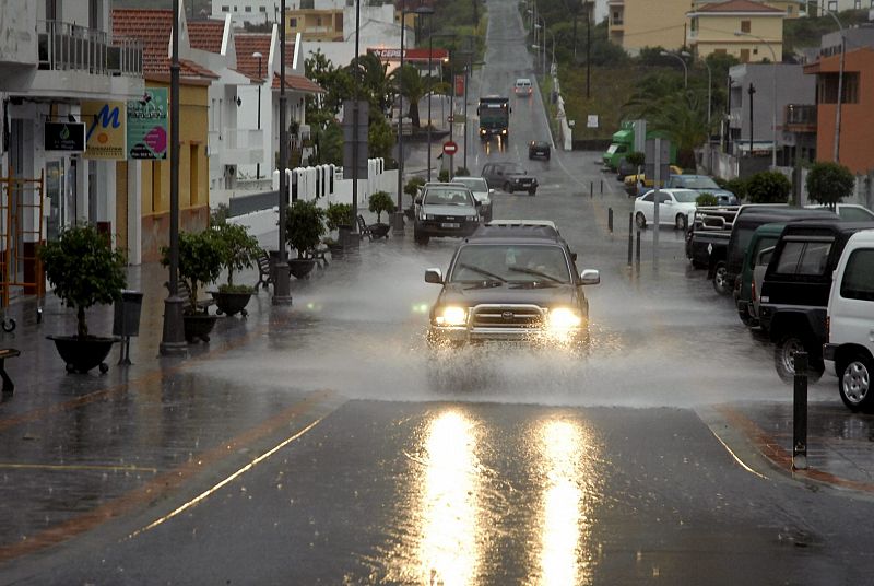 Un coche circula por una calle inundada en el casco urbano de la Frontera, en la isla de El Hierro, que, al igual que las restantes del archipiélago canario, permanece en alerta por vientos y lluvias fuertes.