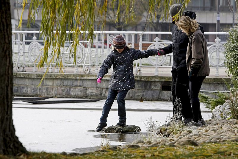 Una niña pisa el hielo formado en uno de los estanques de un parque de Pamplona debido a las bajas temperaturas registradas hoy en la ciudad.