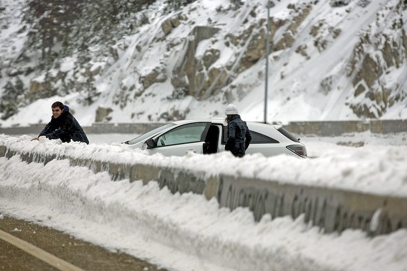 Varias personas disfrutan de la nieve junto a una carretera de Navacerrada (Madrid).