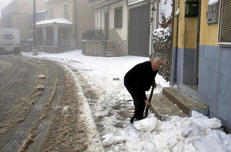 Una mujer retira la nieve del acceso a su vivienda en la localidad salmantina de El Payo, limítrofe con Cáceres, que, según su alcalde, ha amanecido casi aislada a causa de la intensa nevada caída en las últimas horas.