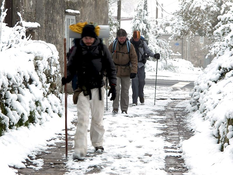 Varios peregrinos caminan con dificultad por un camino nevado. El temporal de frío y nieve mantiene en alerta a numerosas autonomías por nevadas y bajas temperaturas.