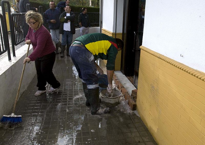 Unos vecinos se preparan para evitar la entrada de agua a sus casas en Écija