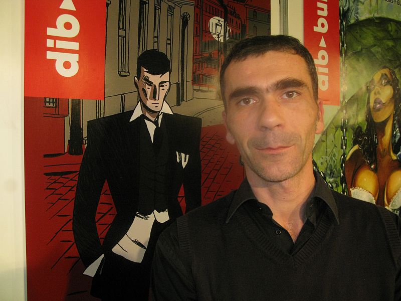 Christian Cailleaux posando junto al cartel de su obra 'Los impostores'