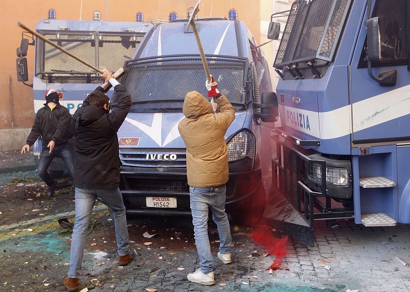 Dos manifestantes intentan destrozar los furgones de la policía durante las protestas