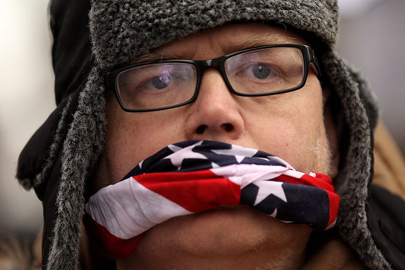 Un manifestante amordazado con la bandera de Estados Unidos protesta ante el tribunal.