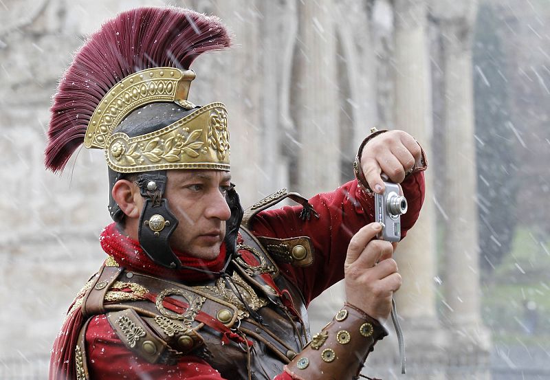 Un hombre disfrazado de centurión romano toma una foto frente al Coliseo, en Roma