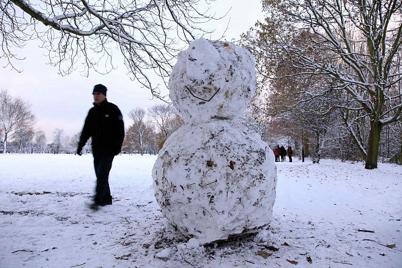 A man walks past a snowman on Wandsworth Common after heavy snow falls in London