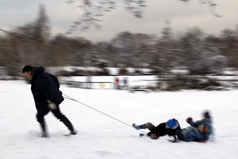 A man pulls children on a sledge on Wandsworth Common after heavy snow falls in London