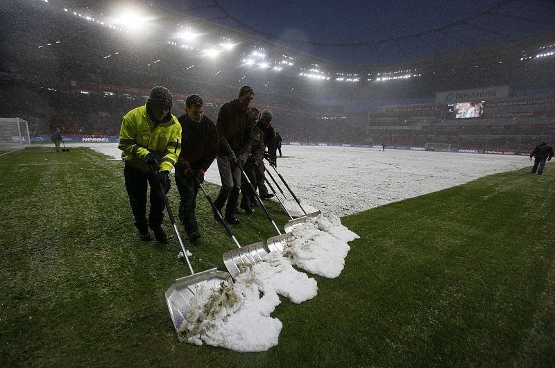 Volunteers shovel snow during half time of the German first division Bundesliga soccer match of Bayer Leverkusen and SC Freiburg in Leverkusen