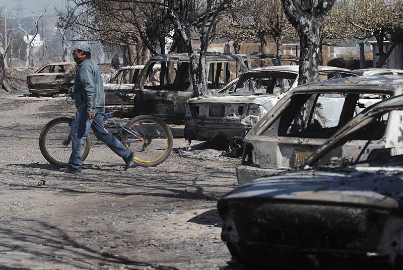 A man walks past burnt cars at the site of an explosion of a Pemex pipeline in the village of San Martin Texmelucan