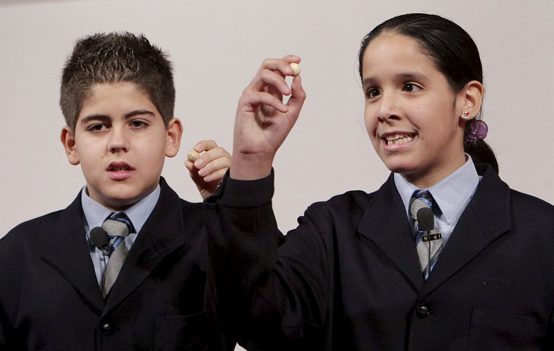 Los niños del Colegio de San Ildefonso María José Posligua y Alejandro Velasco muestran el número 73.684 que ha sido premiado con uno de los quintos premios.