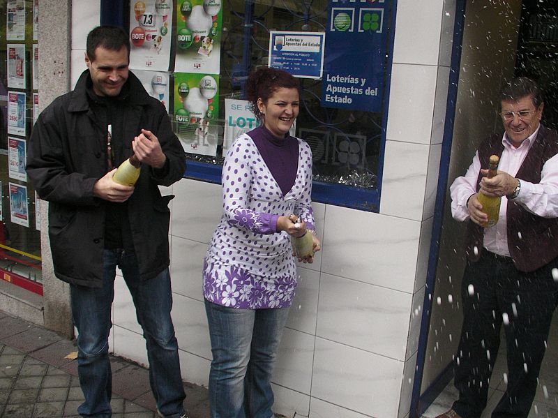 Unos agraciados con el tercer premio del sorteo de Navidad lo celebran a las puertas de la administración.