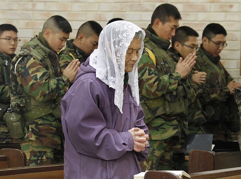 A resident and South Korean marines pray during a Christmas mass at a Catholic church on Yeonpyeong island