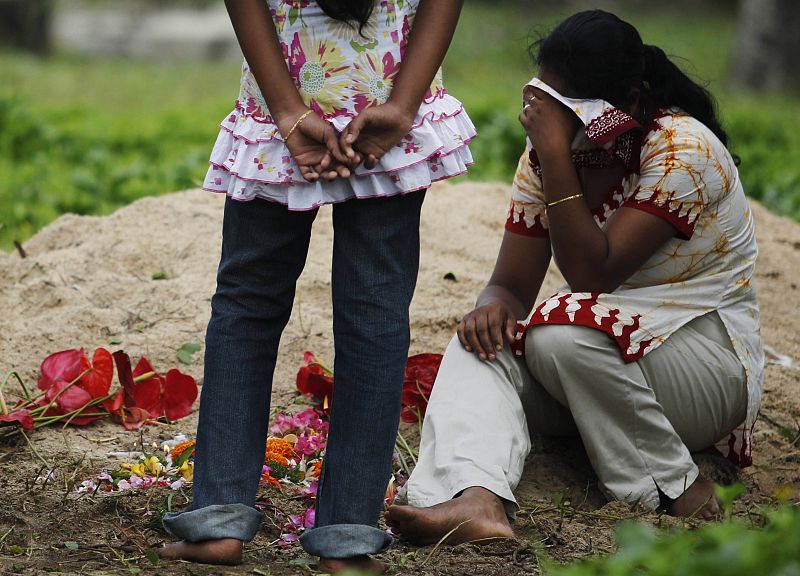 A woman cries near a mass grave for victims killed in the 2004 tsunami at Peraliya, south of Colombo