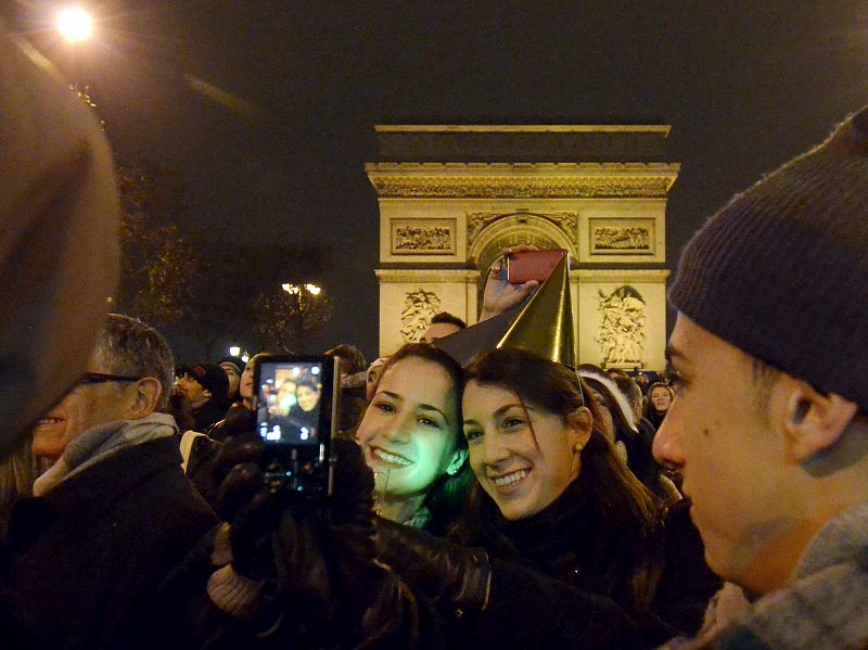 Dos españolas se toman una fotografía frente al Arco del Triunfo, en los Campos Elíseos de París (Francia)
