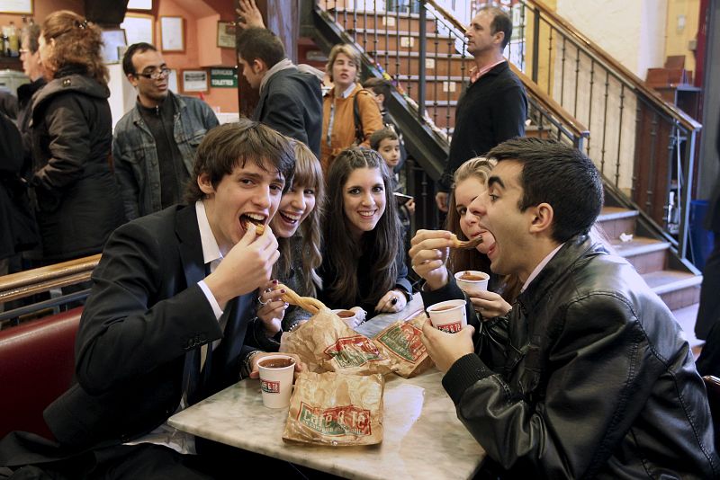 Un grupo de jóvenes toman el tradicional chocolate con churros a primeras horas de la mañana en un local madrileño, tras la celebración de la Nochevieja y el Año Nuevo la pasada madrugada