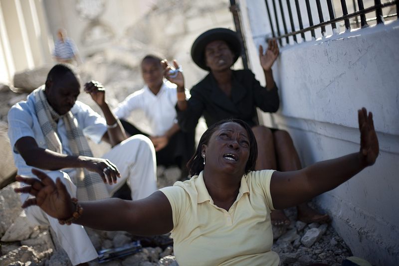 Varias personas asisten a una ceremonia junto a los escombros de la catedral de Puerto Príncipe.