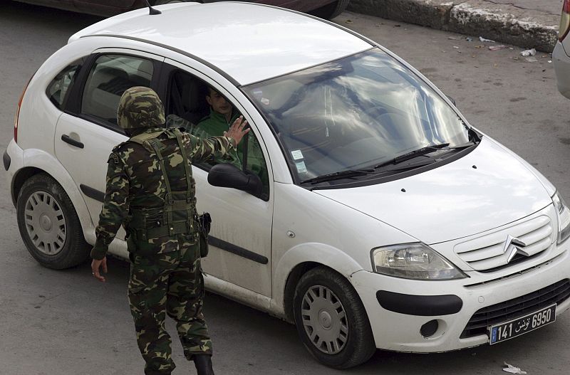 Un soldado tunecino manda detenerse al conductor de un vehículo mientras centenares de personas se manifestan frente al Ministro del Interior en Túnez pidiendo la salida del poder del presidente Ben Alí