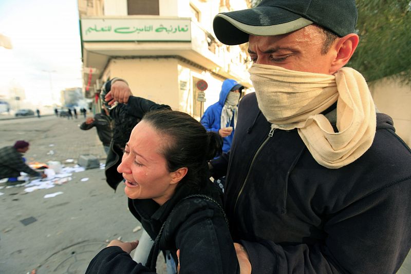Un manifestante lleva a una mujer lloranda durante los enfrentamientos con la policía en Túnez.