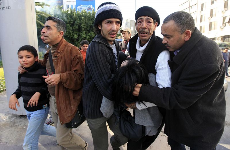 Un grupo de hombres tunecinos lleva en brazos a una mujer insconsciente tras los disturbios.