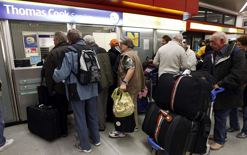 Tourists stand in queue to get information at the counter of Thomas Cook travel agency at Berlin's Tegel airport