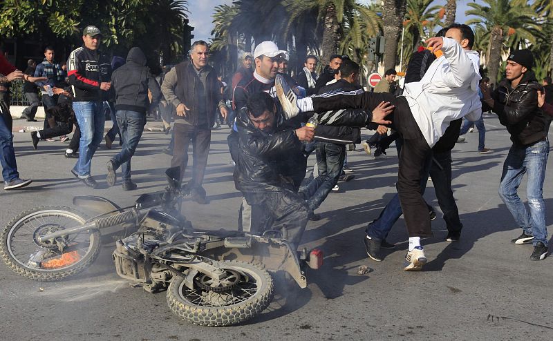 A protester hits a policeman during clashes with riot police in downtown of the capital Tunis