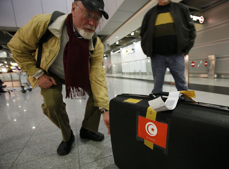 A German tourist grabs his suitcase after returning to Duesseldorf airport from Tunis