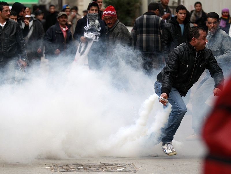 Manifestantes tiran latas con gas lacrimógeno a la policía en el transcurso de los dissturbios que han tenido lugar este martes en Túnez.