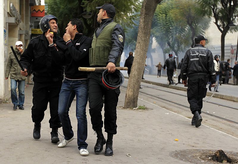 Dos policías antidisturbios detenienen a otro hombre que se manifestaba este martes en Túnez