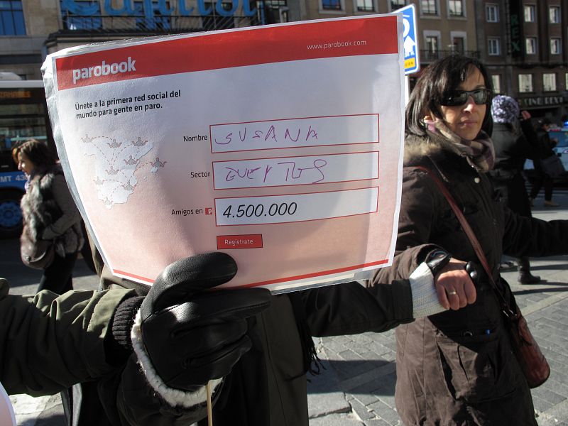 Una de los manifestantes de la cadena humana contra el paro muestra el cartel de Parobook.