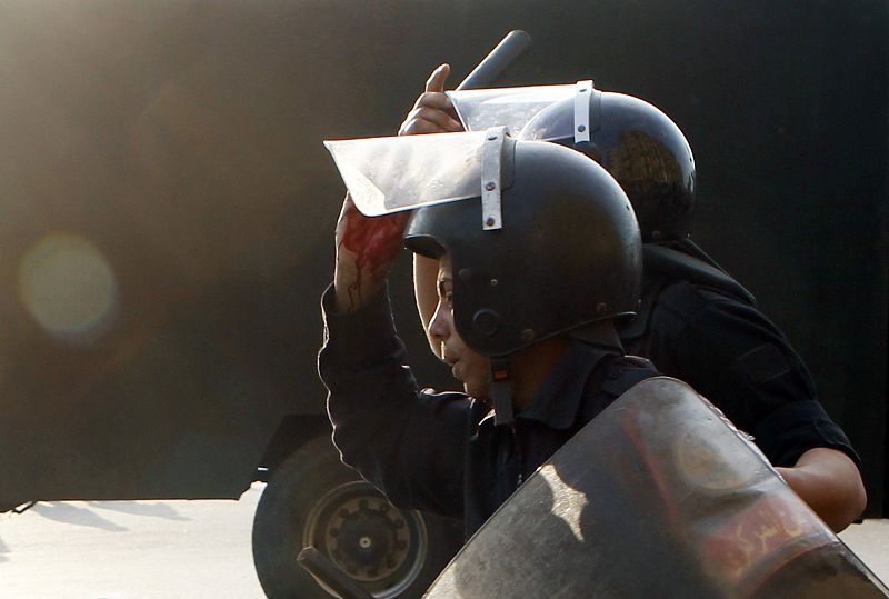 Un policía antidisturbios con una mano ensangrentada trata de disolver a los manifestantes.