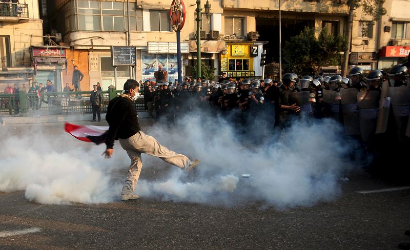 Un joven da una patada a un bote de gases lacrimógenos disparado por unos policías antidisturbios mientras miles de personas se manifiestan