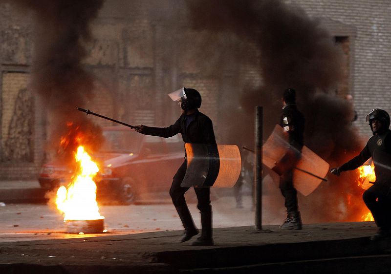 Un policía antidisturbios junto a una barricada ardiendo durante los enfrentamientos en El Cairo.