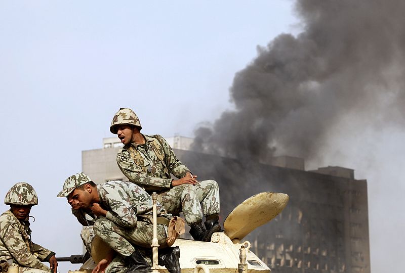 Egyptian soldiers sit on top of an armoured vehicle in Cairo