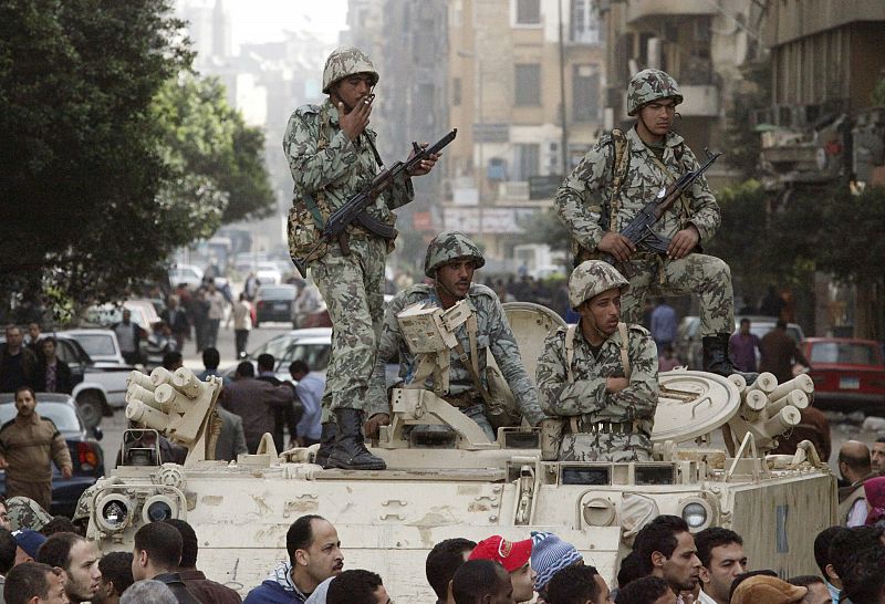 Egyptian soldiers stand on top of an armoured vehicle in Cairo