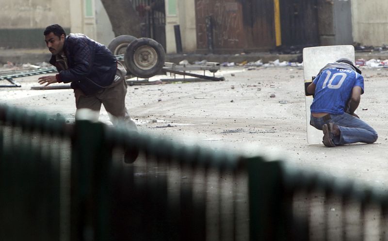 An Egyptian anti-government protester shields himself during clashes with riot police at Tahrir Square in downtown Cairo