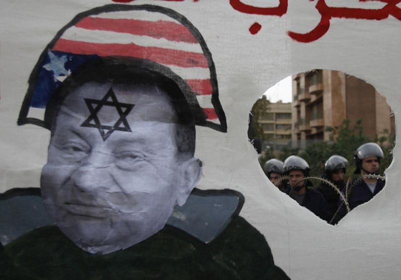 Riot police are pictured through a banner with an image of Egypt's President Mubarak during a sit-in organised by Lebanese activists in front of the Egyptian embassy in Beirut