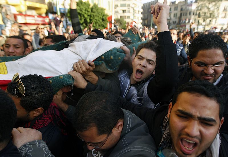 Protesters carry the body of a man killed during an attempt to storm the interior ministry in Cairo