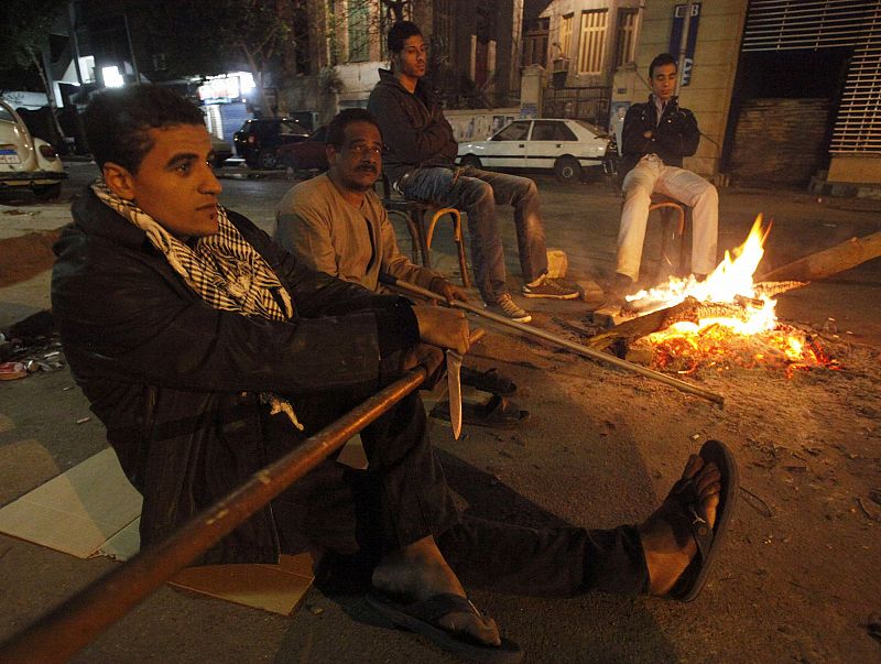 Local residents sit around a fire as they secure property and families from looters in Cairo