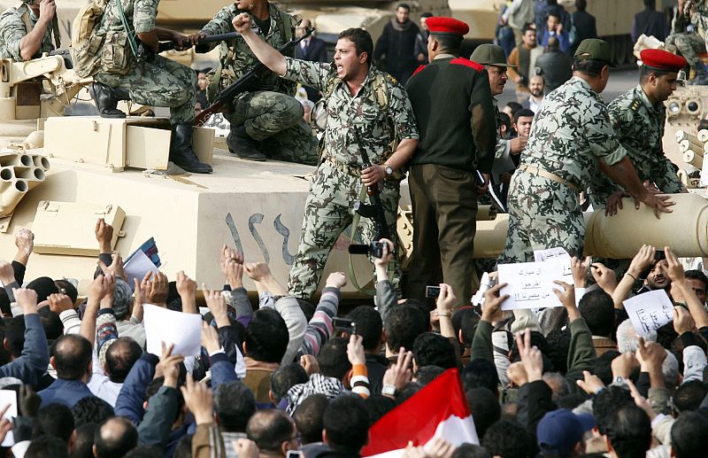 An Egyptian Army soldier gestures to a crowd as he stands atop a tank in Cairo