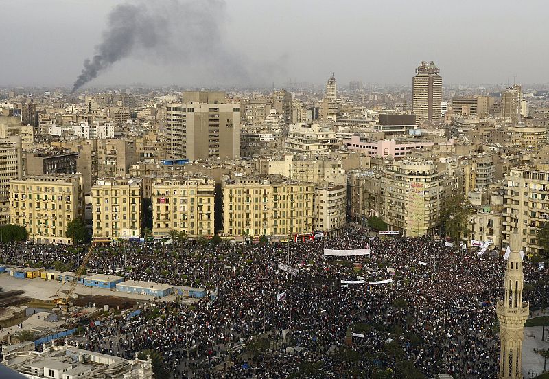 Miles de egipcios se concentran en plaza Tahrir, que se ha convertido en el símbolo de las protrestas, mientras que a lo lejos se aprecia una nube de humo, de origen desconocido.