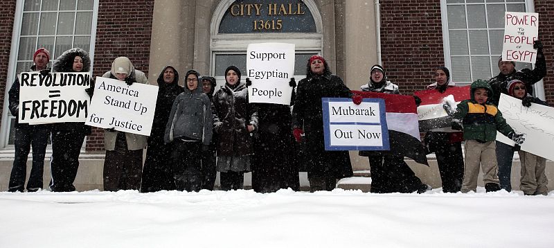 Egyptian-Americans stand in snow outside City Hall holding signs demanding Egypt's President Mubarak step down during demonstration in support of Egyptian protesters, in Dearborn