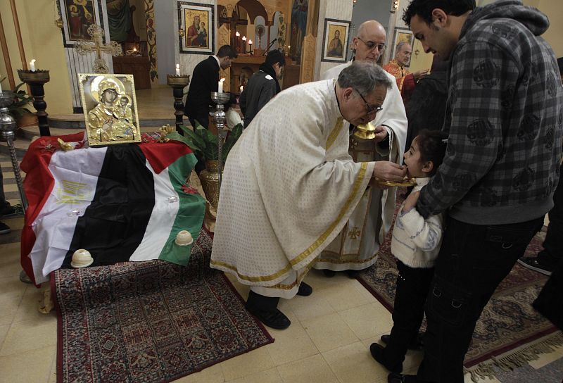 A girl receives Holy Communion from a priest in the West Bank town of  Bethlehem