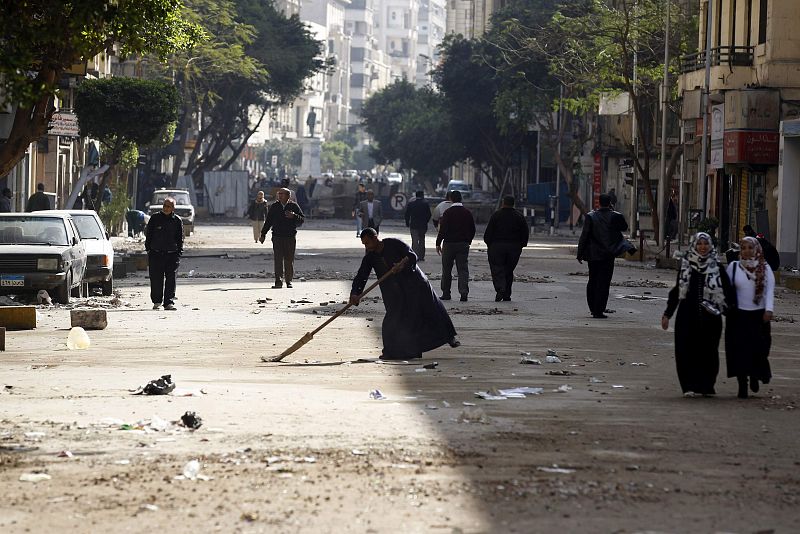 A man sweeps the road as opposition supporters make their way to Tahrir Square in Cairo