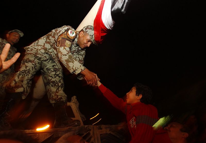 Un padre alza a su hijo para dar la mano a un oficial del ejército