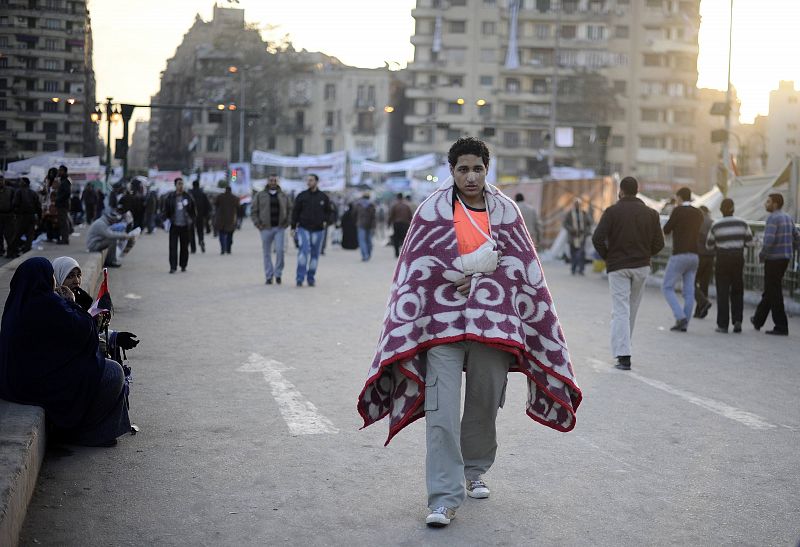 Un egipcio, herido en las manifestaciones, camina por la plaza Tahrir que amanece tras la salida de Mubarak.