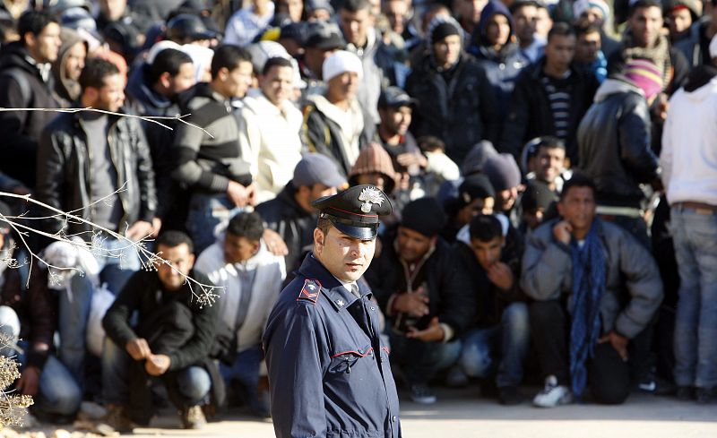 Un policia Carabinieri frente a los inmigrantes ilegales procedentes de Túnez.