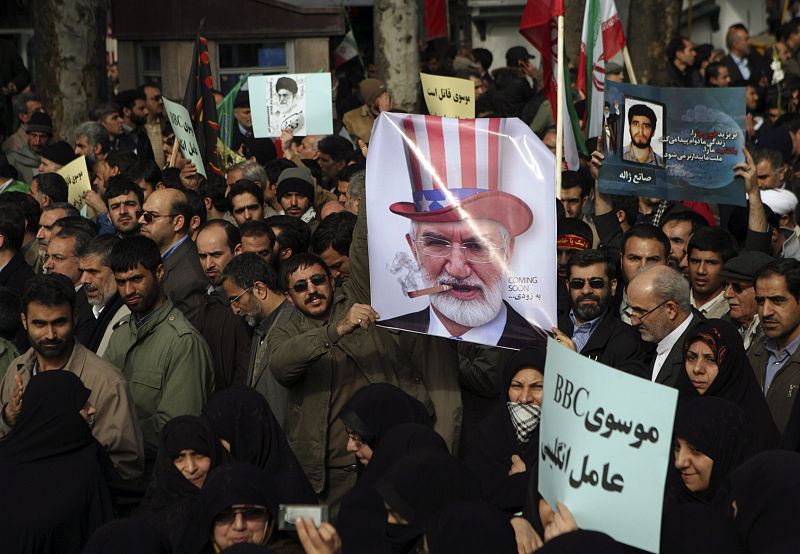 Manifestantes iraníes con un cartel en el que se ataca al líder opositor Mehdi Karroubi