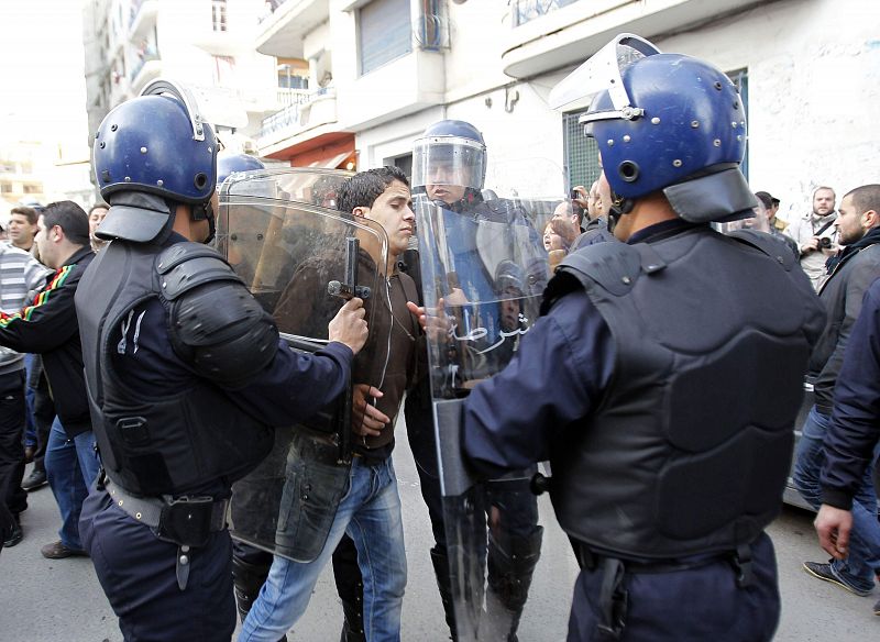 Police riot detain a protester during a demonstration in Algiers